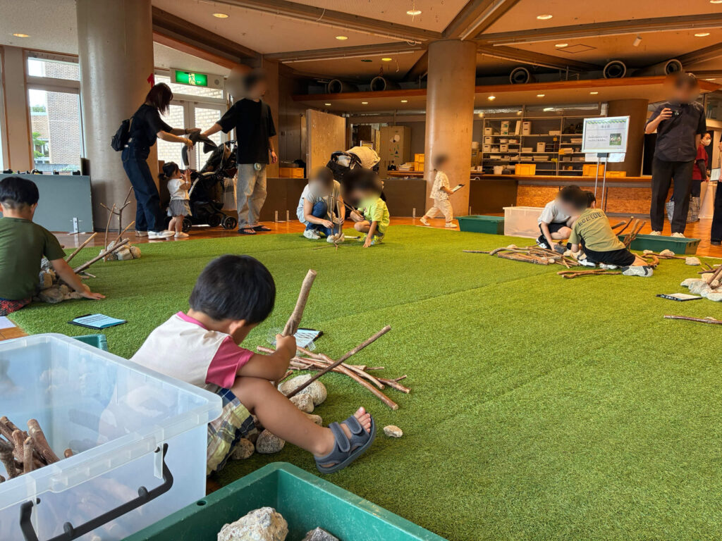 子どもたちが木や石で作品を組み立てている